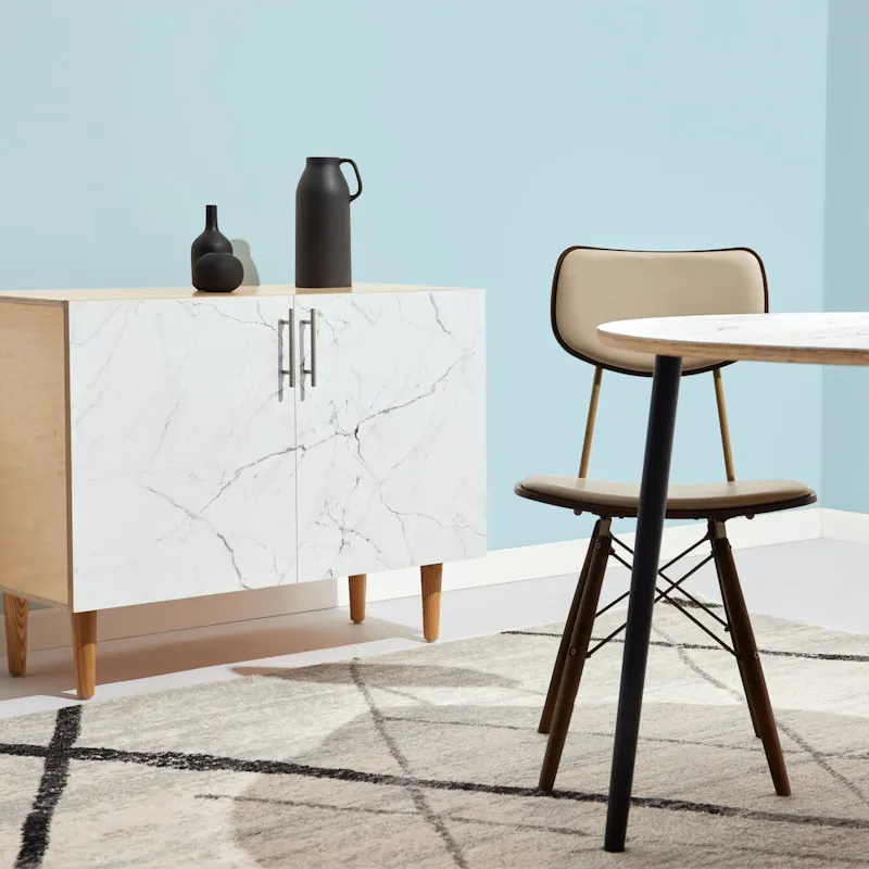 A cream upholstered dining chair beside a marble cabinet.