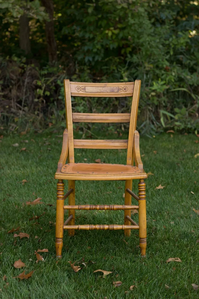 A vintage yellow-painted farmhouse chair on a grass lawn.